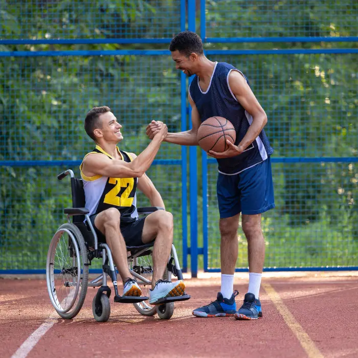 Disabled man in wheelchair playing basketball with a friend