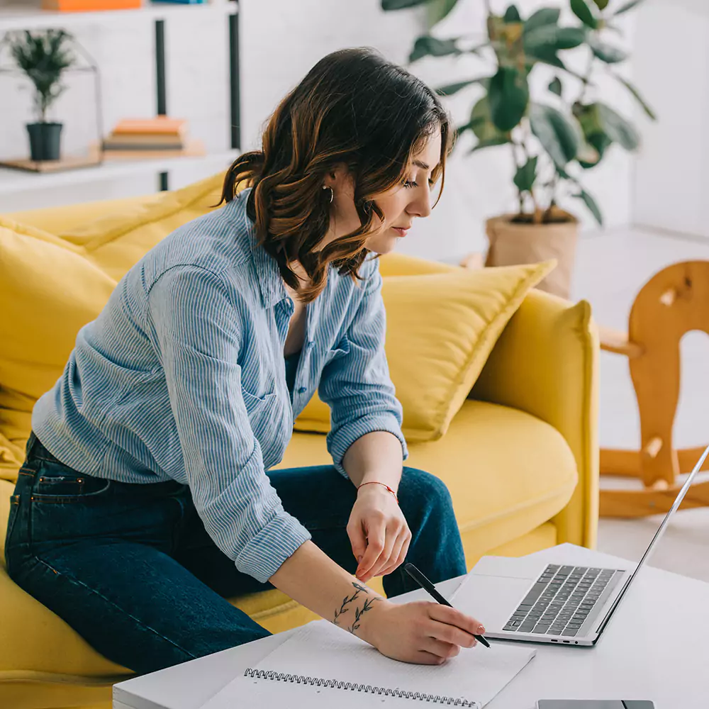 A woman taking notes while using her laptop