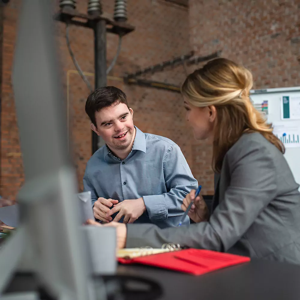 A down syndrome man learning about office work with a care giver