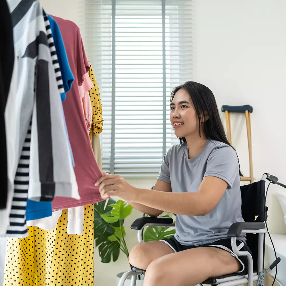 A disabled woman in a wheelchair picking our an outfit to wear