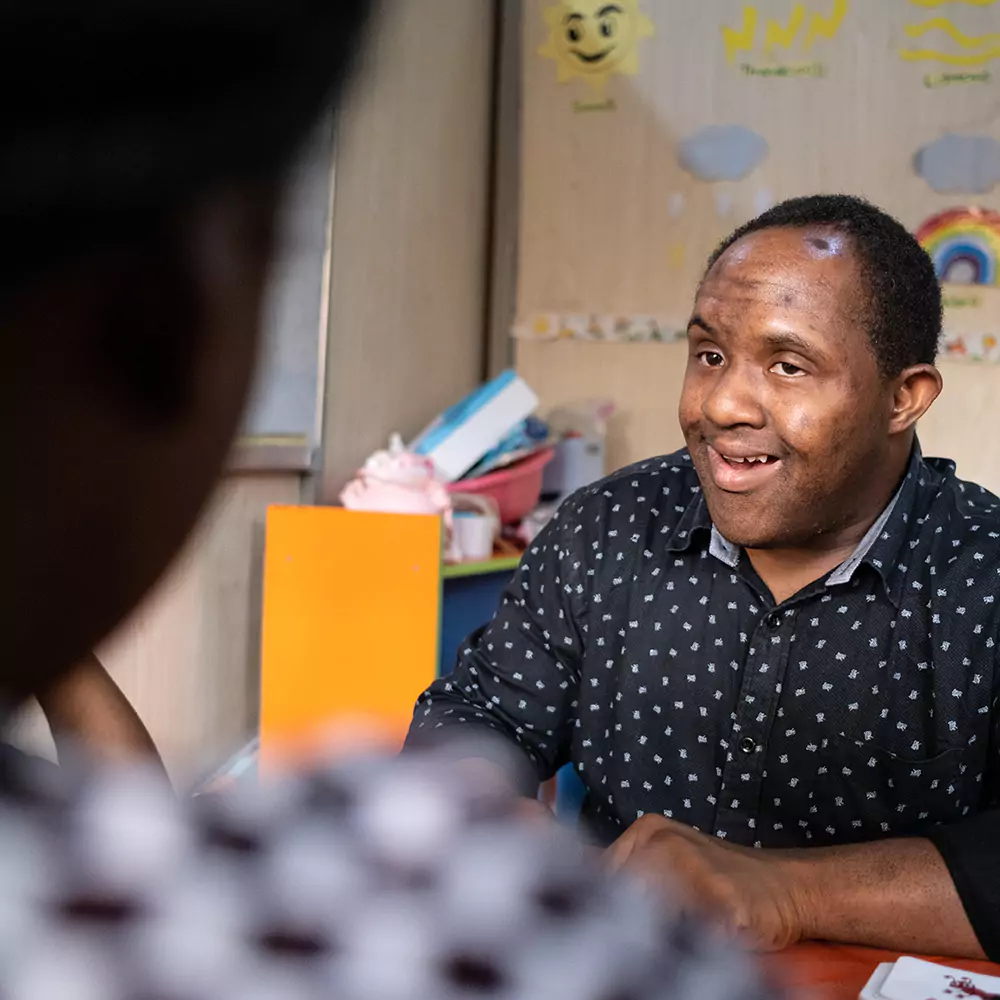 A down syndrome man having a chat with a care giver