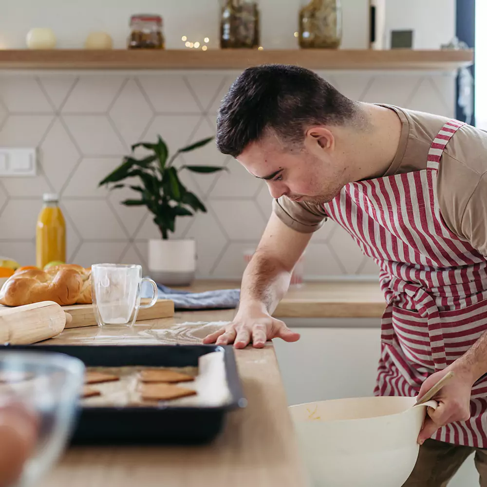 A down syndrome man baking cookies in the kitchen